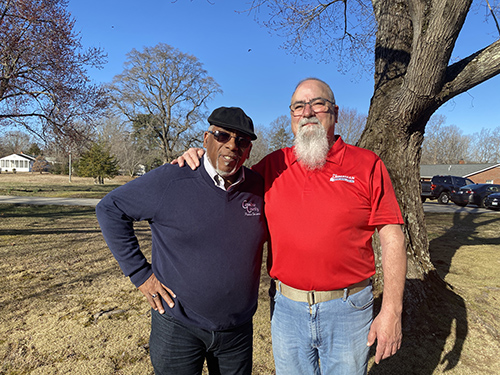 Rick standing with Calvin Taylor in front of a tree