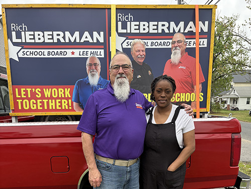 Rich standing with Mona Van in front of campaign signs