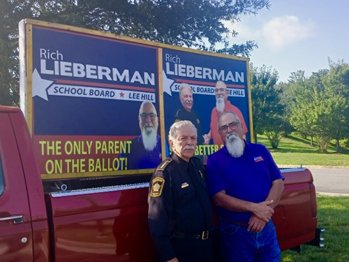 Sheriff Harris and Rich in front of campaign signs